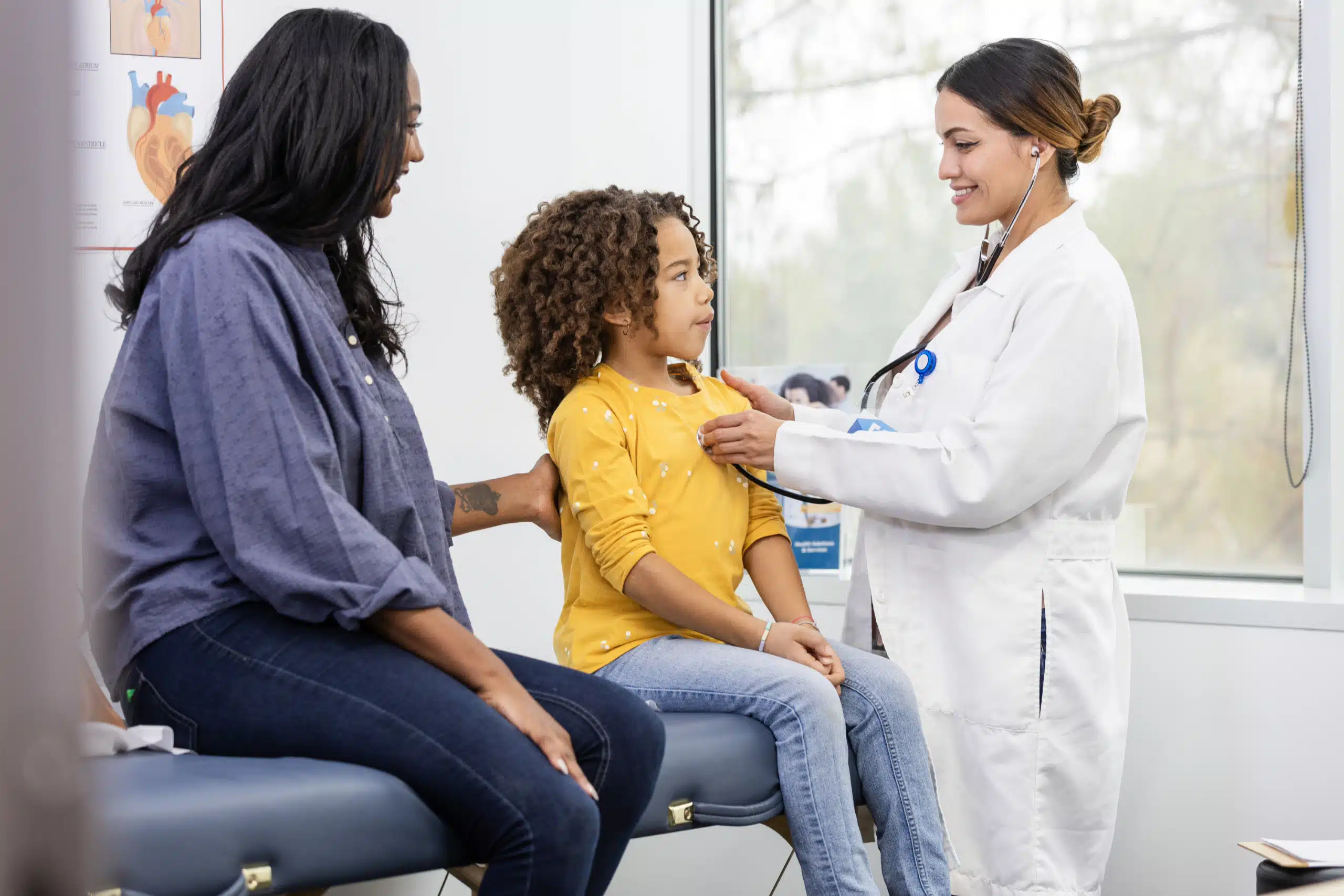A girl sits up tall so the doctor can listen to her heart