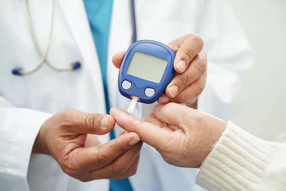 Doctor using digital glucose meter for check sample blood sugar level to treatment diabetes.