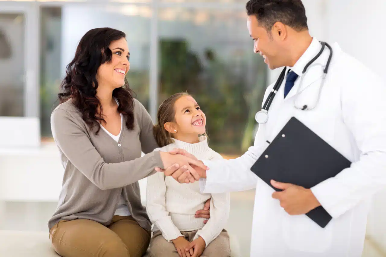 A doctor greeting patient's mother before medical checkup